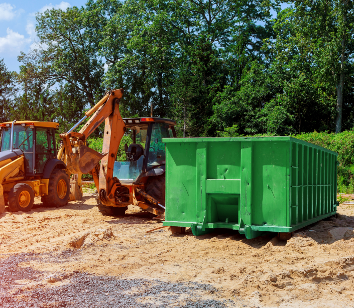 Green construction dumpster on a job site next to excavators